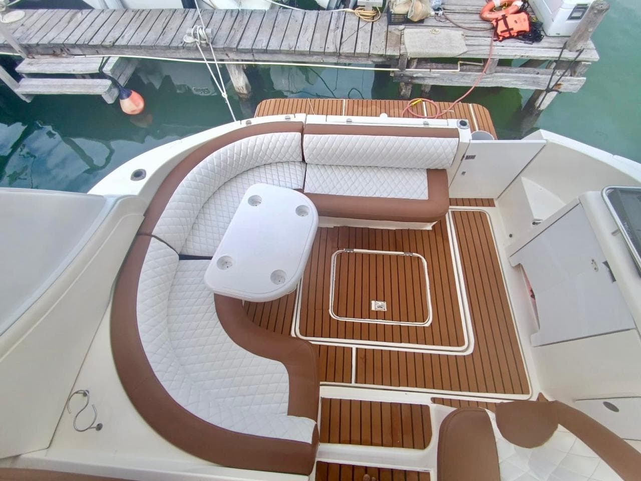 Bathtub with curved sofa, table, and teak floor, docked at the pier.