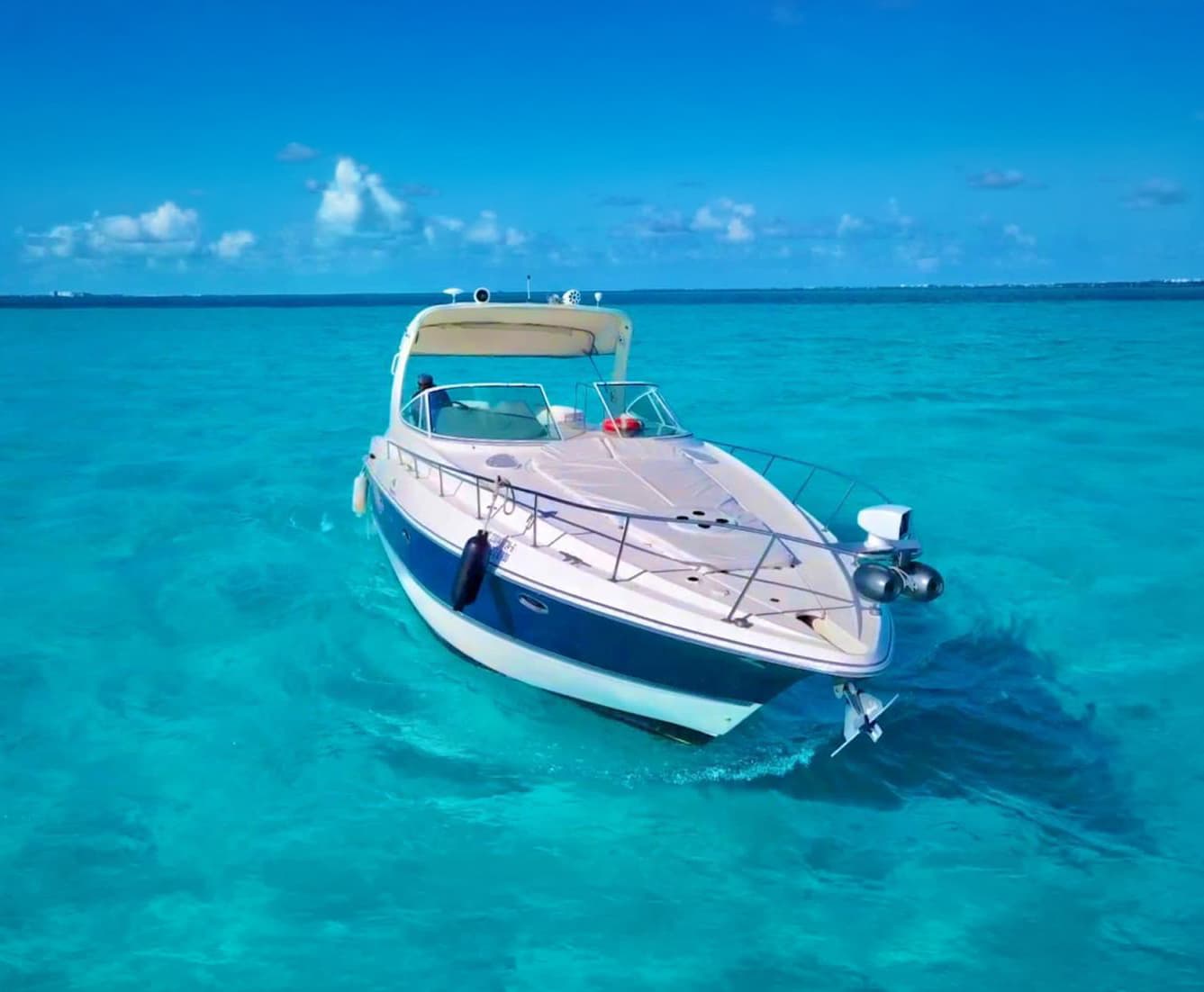 The anchored yacht, viewed from the bow, in very clear water.