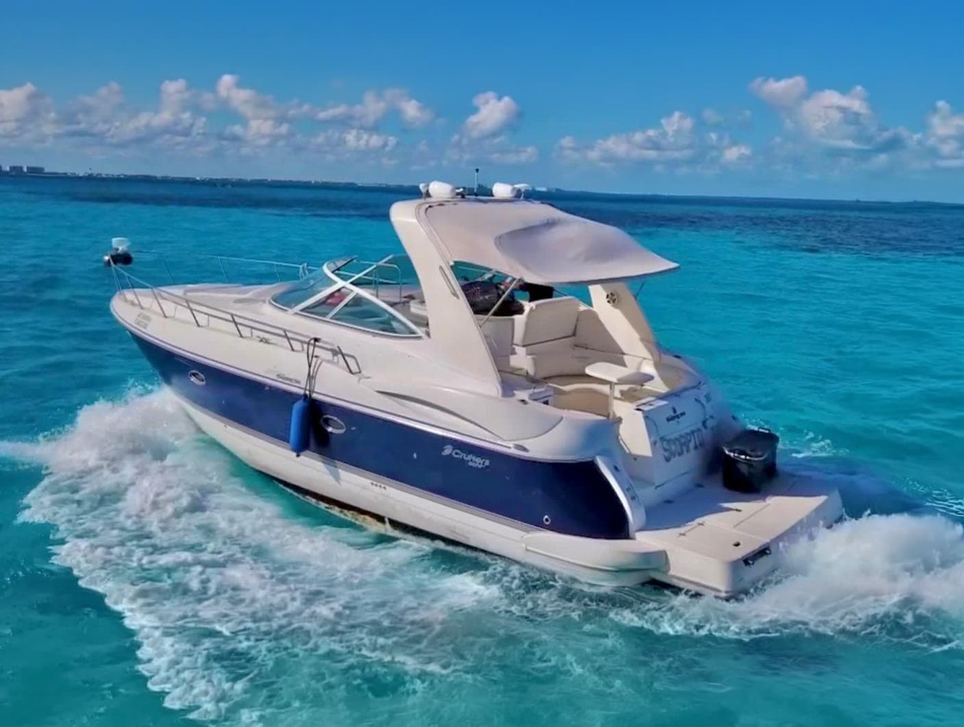 The yacht in motion, with the navy blue hull over turquoise water.