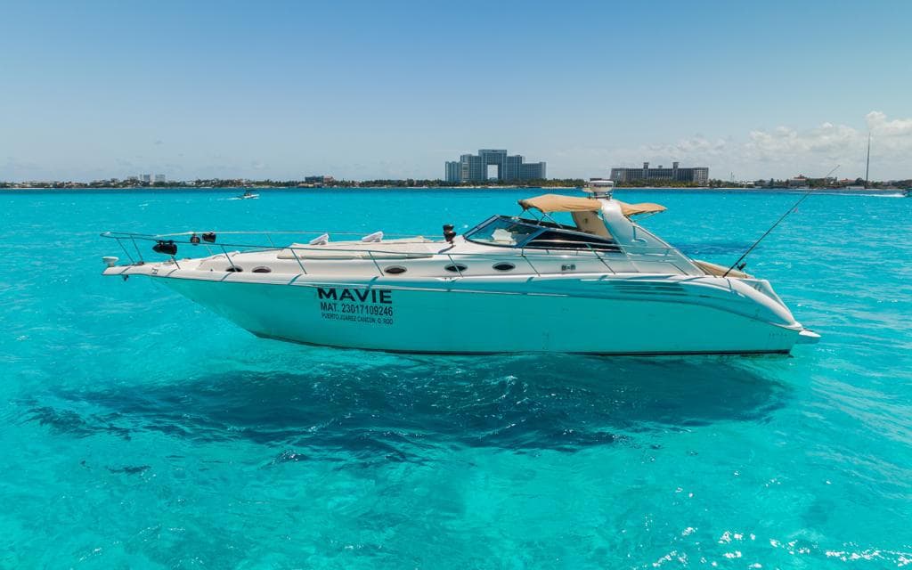 The yacht anchored in three quarters, with the hotel zone in the background.
