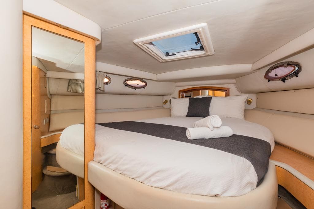 Cabin with double bed, folded towels, and hatch.