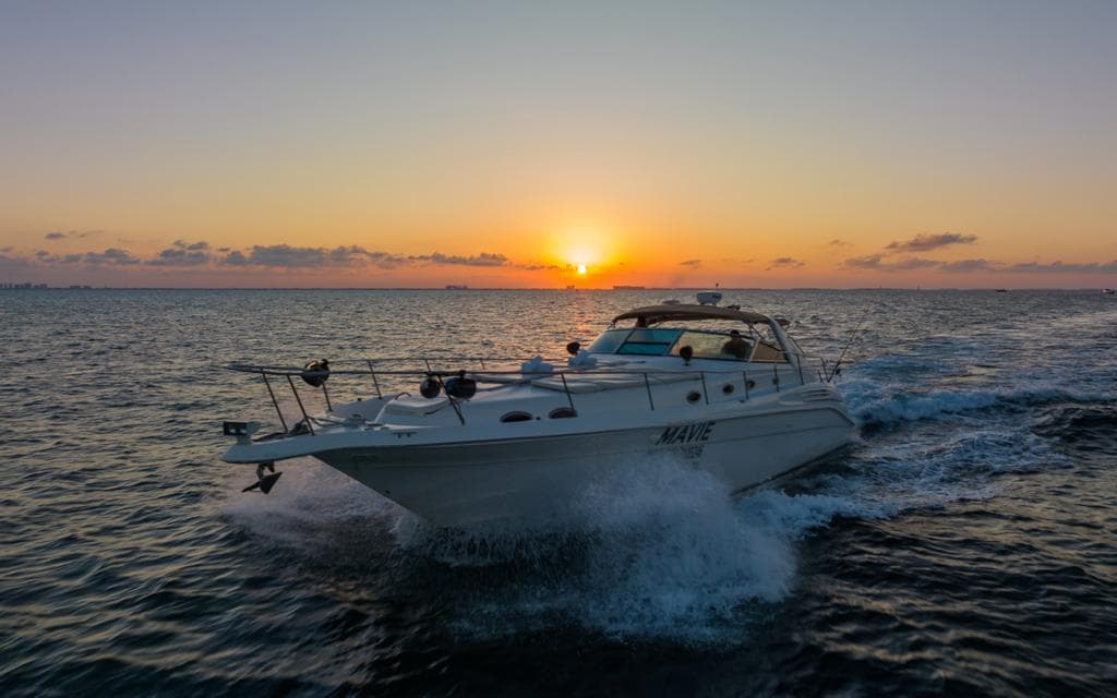 The yacht sailing at sunset, with the sun on the horizon.