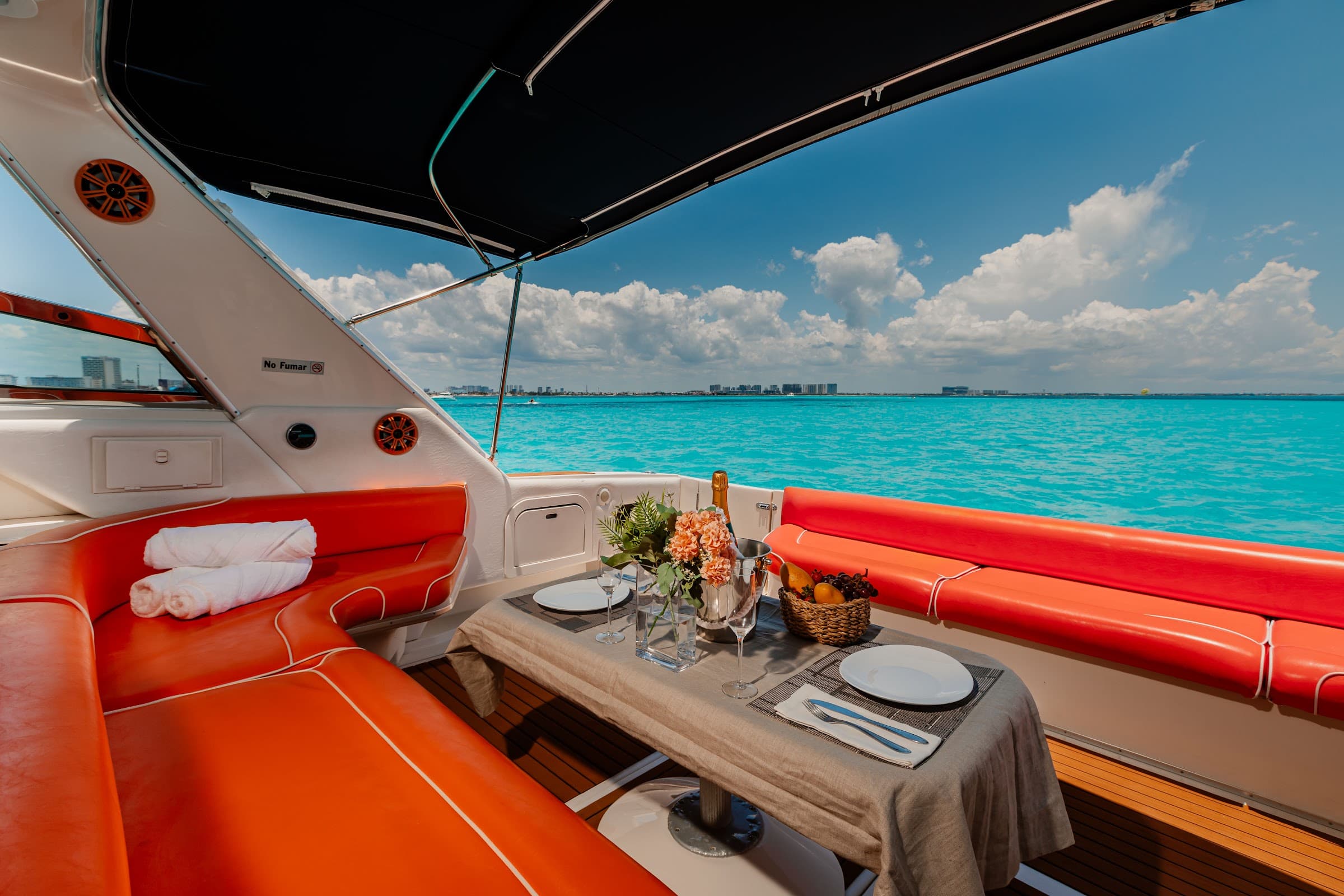 Table set in the stern, with orange sofas and awning.