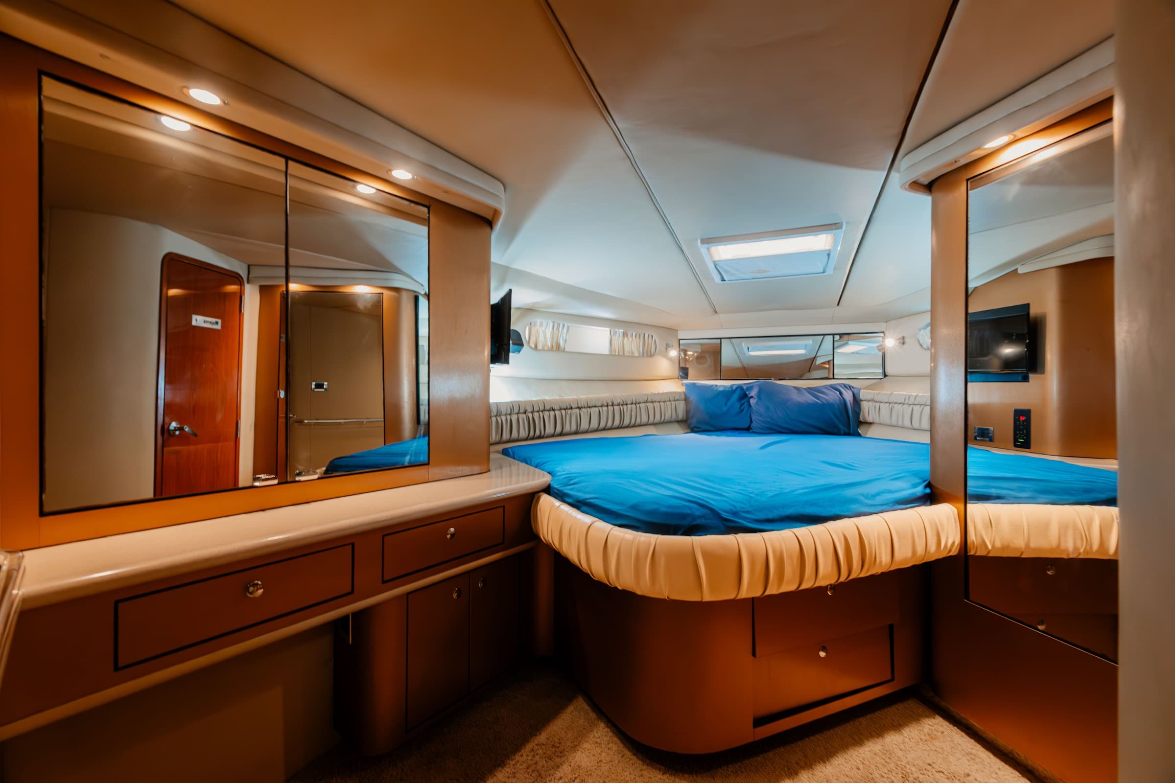 Cabin with a double bed dressed in blue and a mirror.