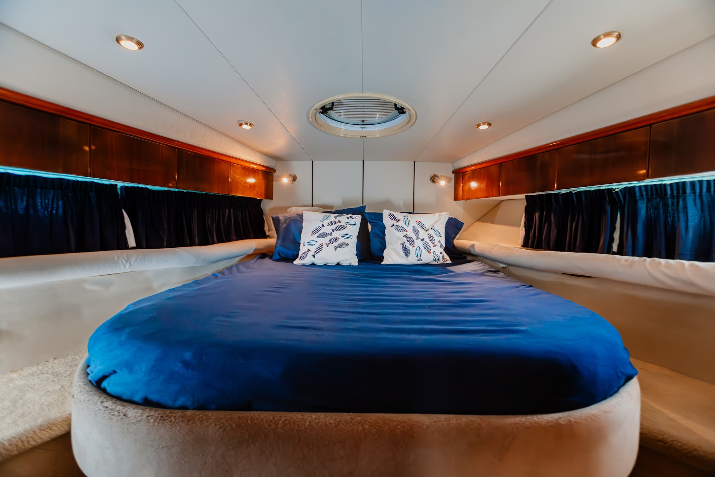 Cabin with a double bed dressed in blue under a hatch.