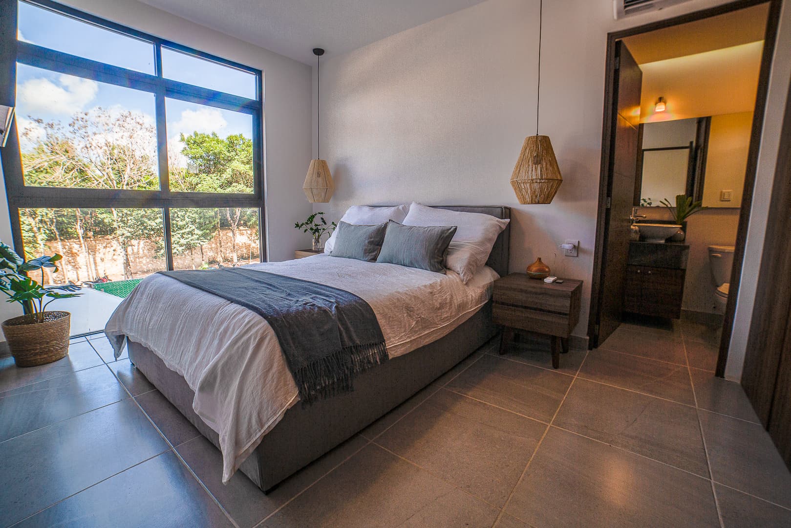 Bedroom with a queen bed, hanging lamps, and a window to the garden.