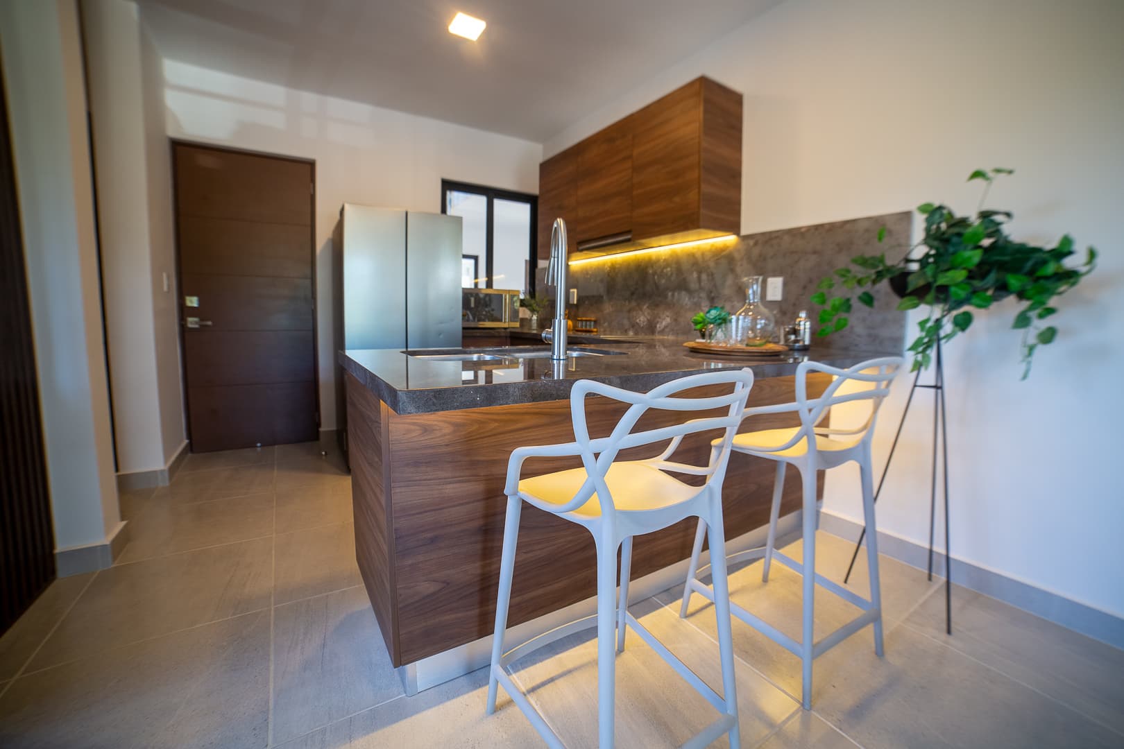 Kitchen with a wood island, refrigerator, and white stools.