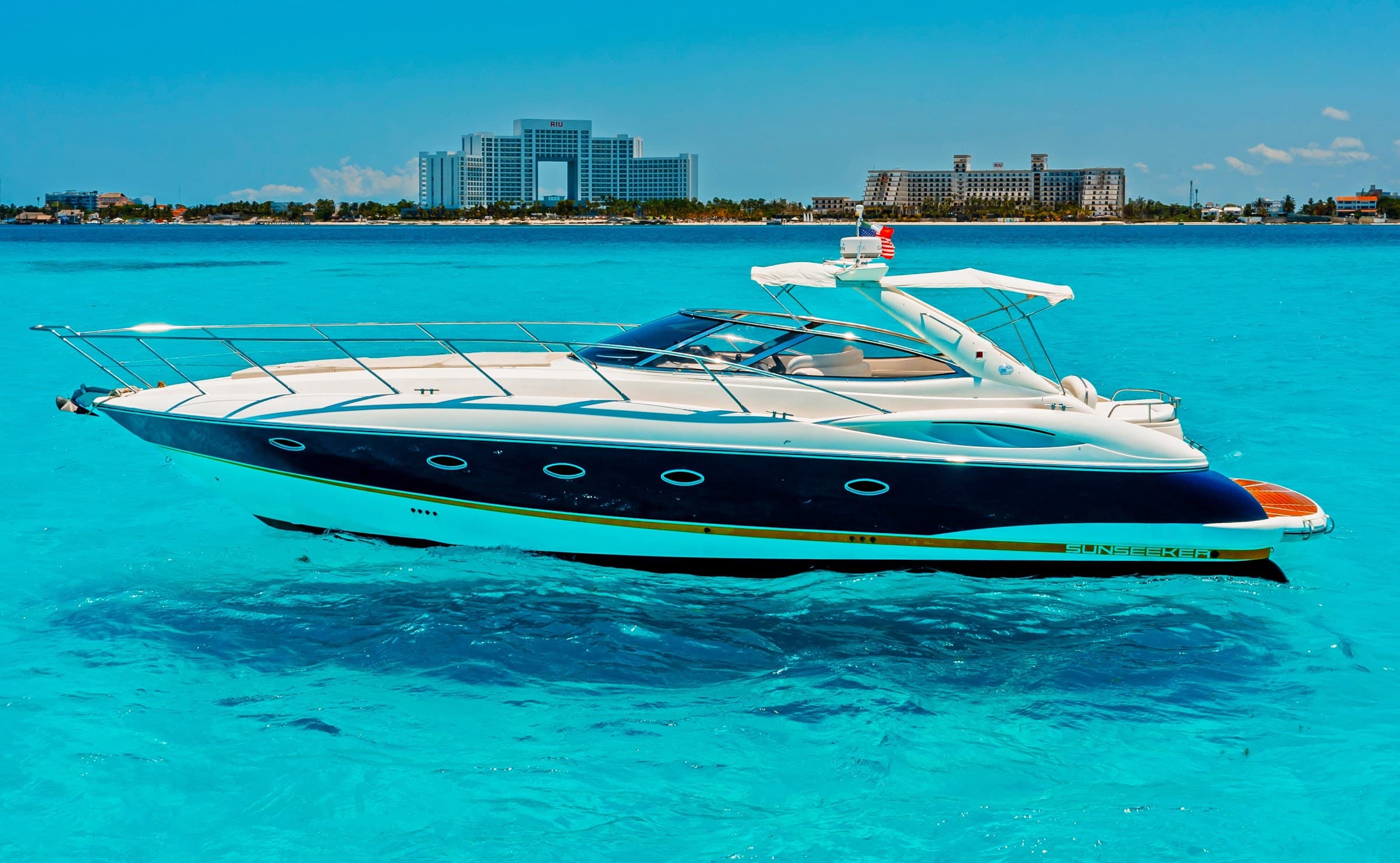 The yacht anchored in turquoise water, with the hotel zone of Cancún in the background.
