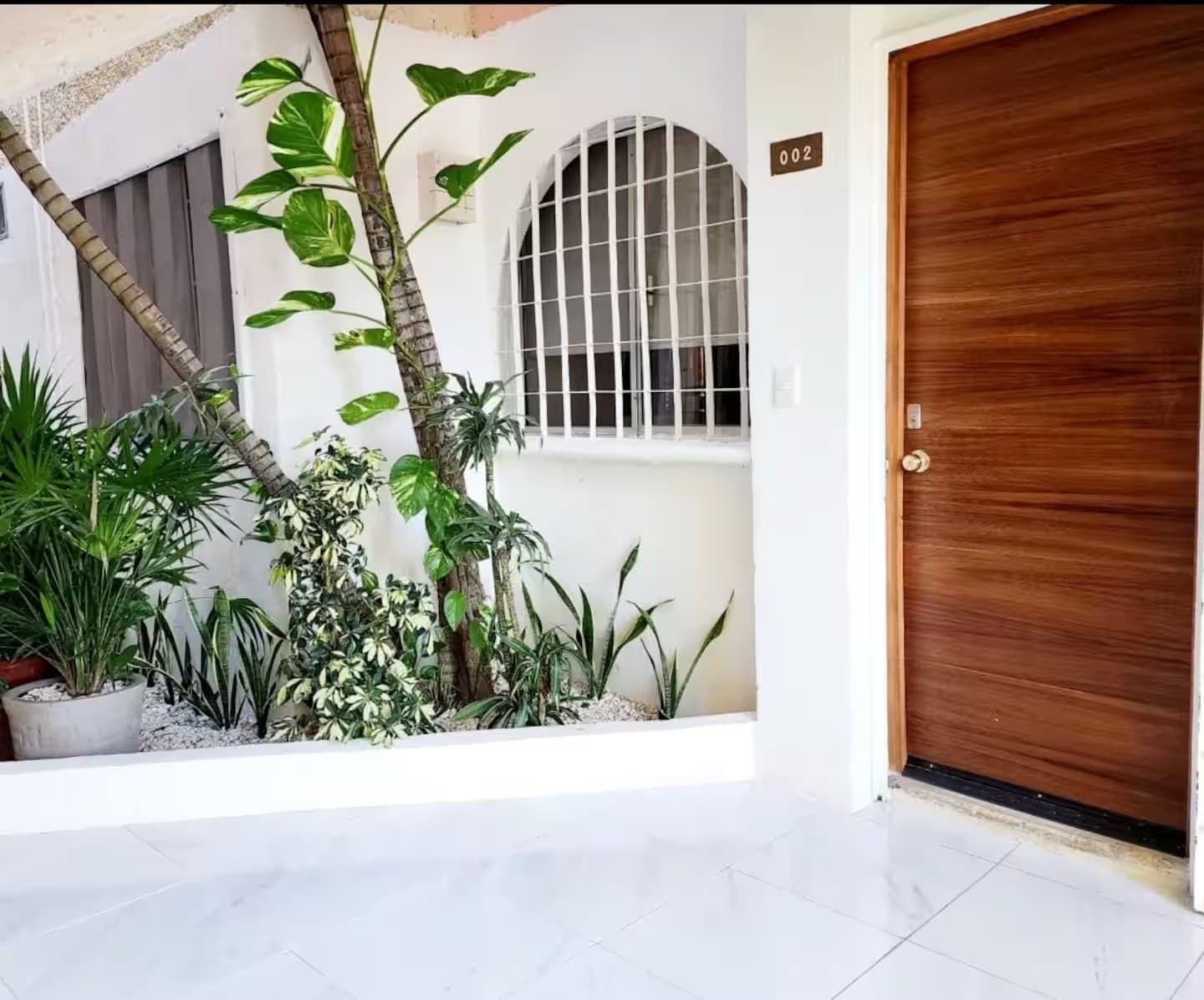 Access to the apartment: wooden door and a small garden next to the entrance.