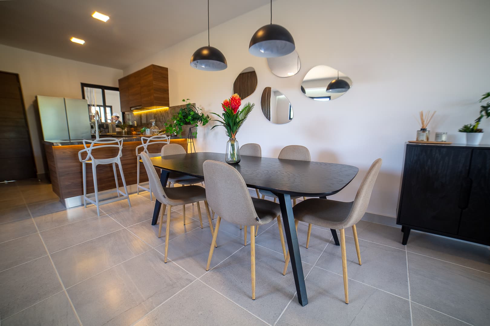 Dining room with an oval table, six chairs, and round mirrors on the wall.