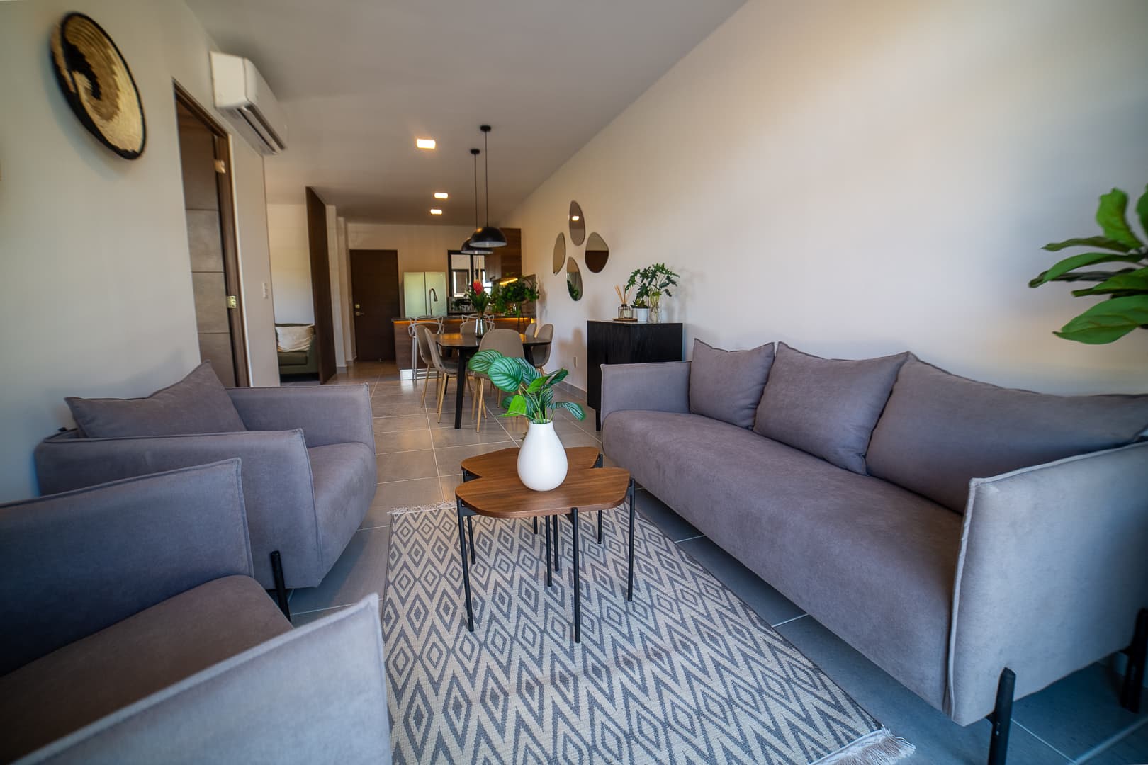 Room with gray sofas, geometric rug, and the dining area at the back.